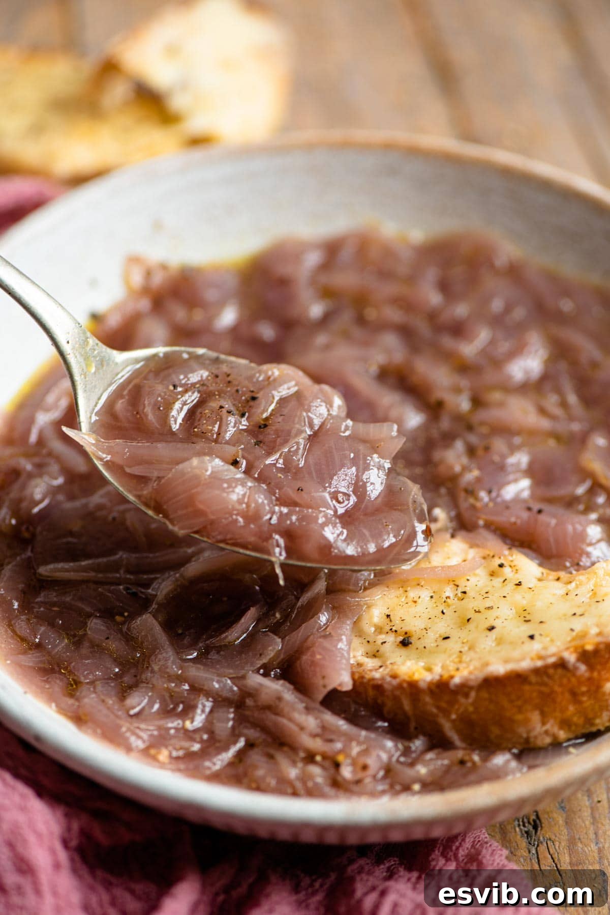 A close-up shot of a spoonful of Carabaccia Tuscan Onion Soup, highlighting its rich, amber color and tender onion strands.