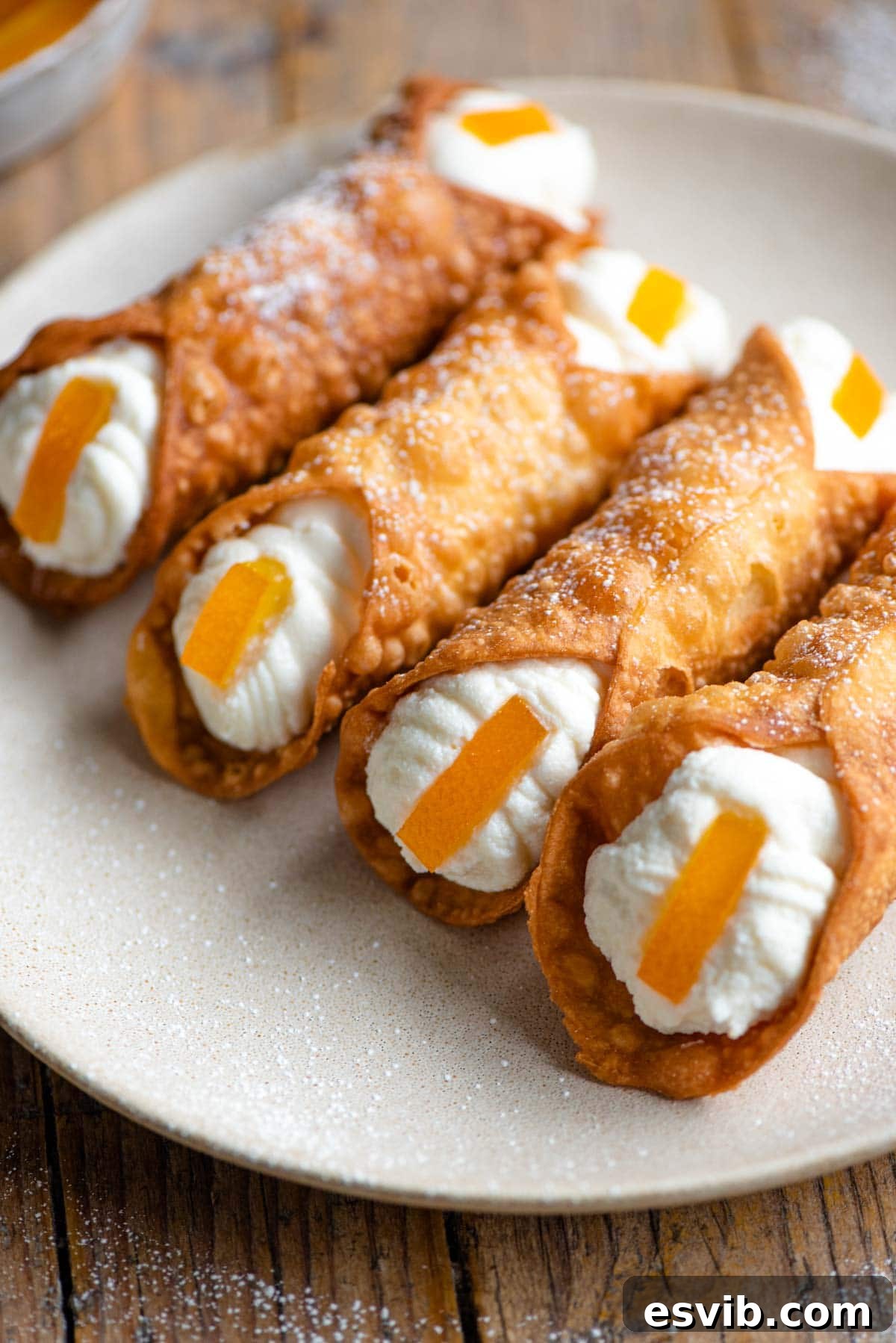 A vibrant close-up of four delicious homemade cannoli, generously filled with creamy ricotta cheese, showcasing their exquisite texture and traditional charm, garnished with candied orange.