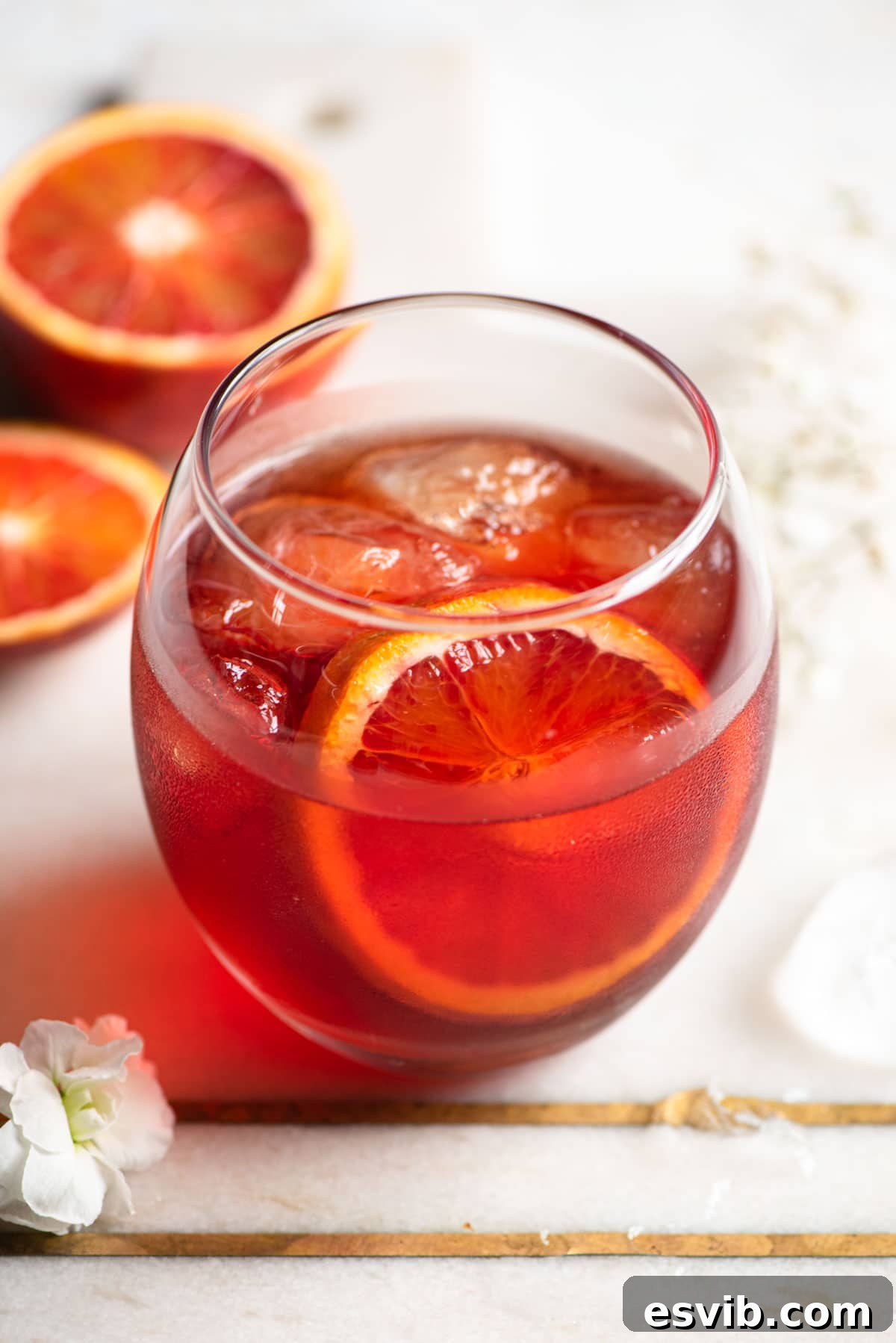 A close up of a Negroni Sbagliato in a round glass, with a slice of orange for garnish