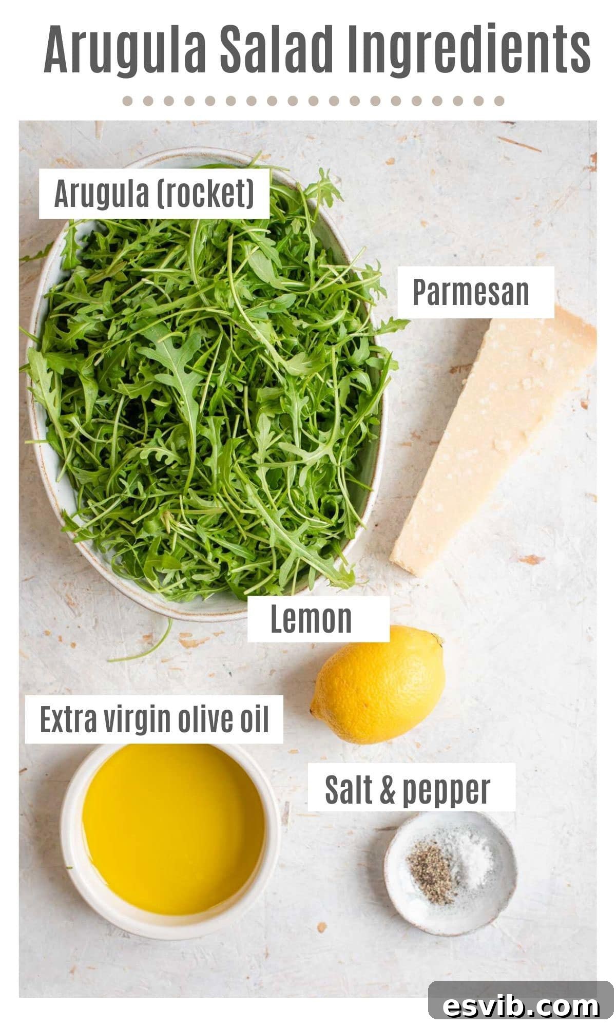 An overhead shot showcasing all the fresh ingredients needed to make a simple arugula salad: arugula, parmesan, lemon, olive oil, and black pepper.