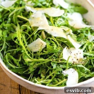 A close up of an arugula salad with parmesan shavings