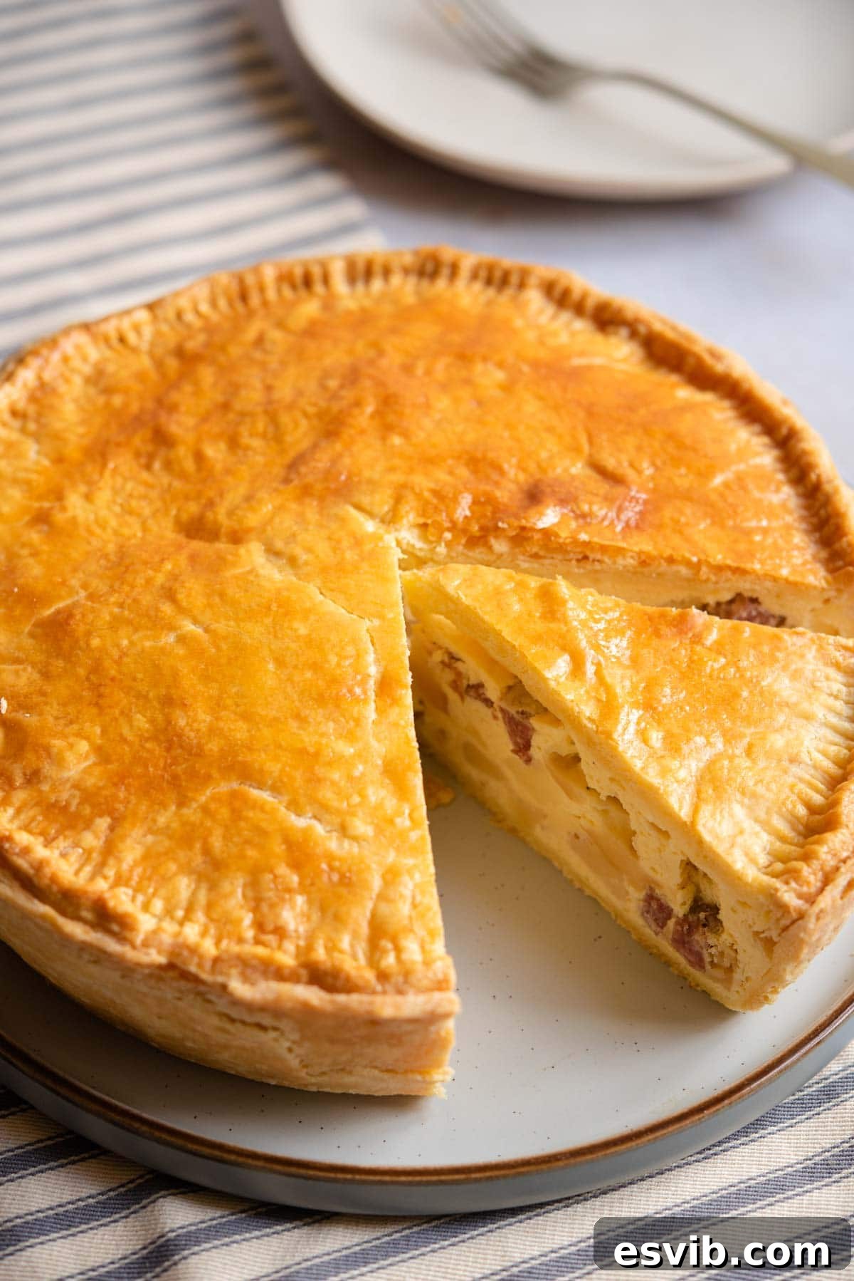 Classic Italian Easter Pie 2 Pizza Rustica on a serving plate with a slice cut, showcasing its rich, layered filling and golden crust.