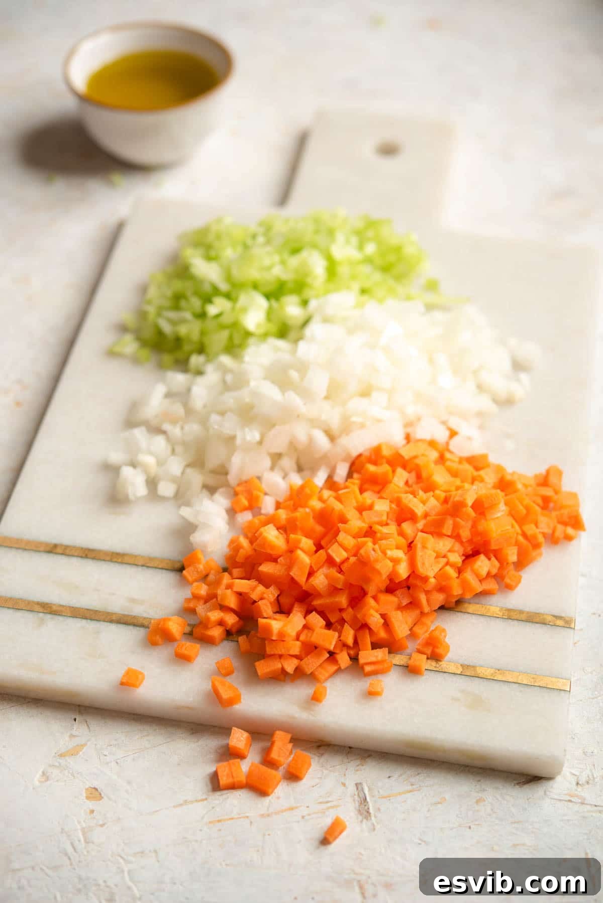 The Art of Perfect Soffritto 2 Finely chopped carrot, celery and onion on a chopping board, ready to be cooked into Italian soffritto