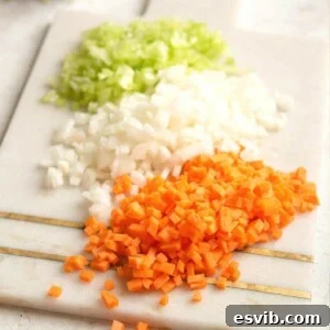 A close up of finely chopped carrot, celery and onion on a cutting board, ready for a batch of homemade soffritto