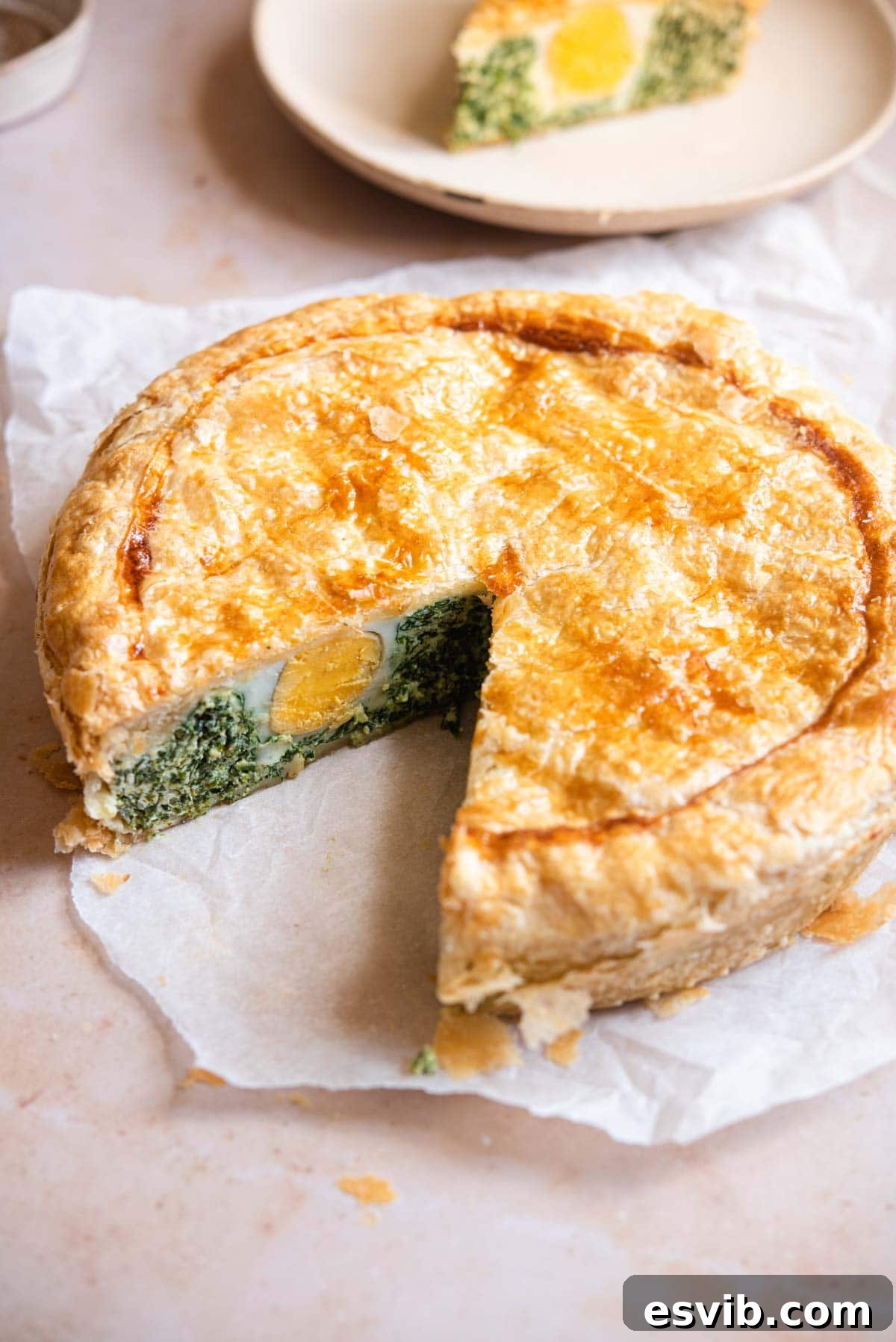 Torta Pasqualina Savory Spinach and Ricotta Easter Pie 2 A beautifully baked Torta Pasqualina, a Ligurian Easter pie, with a slice removed to show the vibrant spinach and ricotta filling with whole eggs.