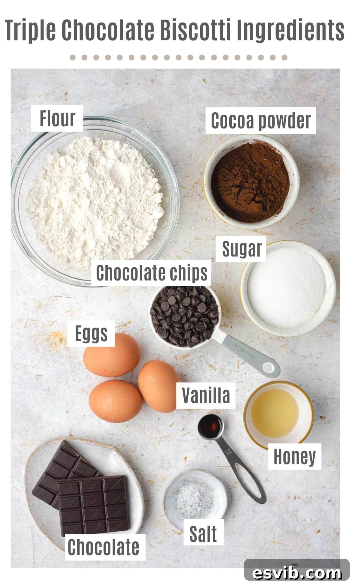 An overhead shot displaying all the carefully measured ingredients laid out on a clean surface, including flour, cocoa powder, sugar, eggs, honey, vanilla, salt, and various chocolates.