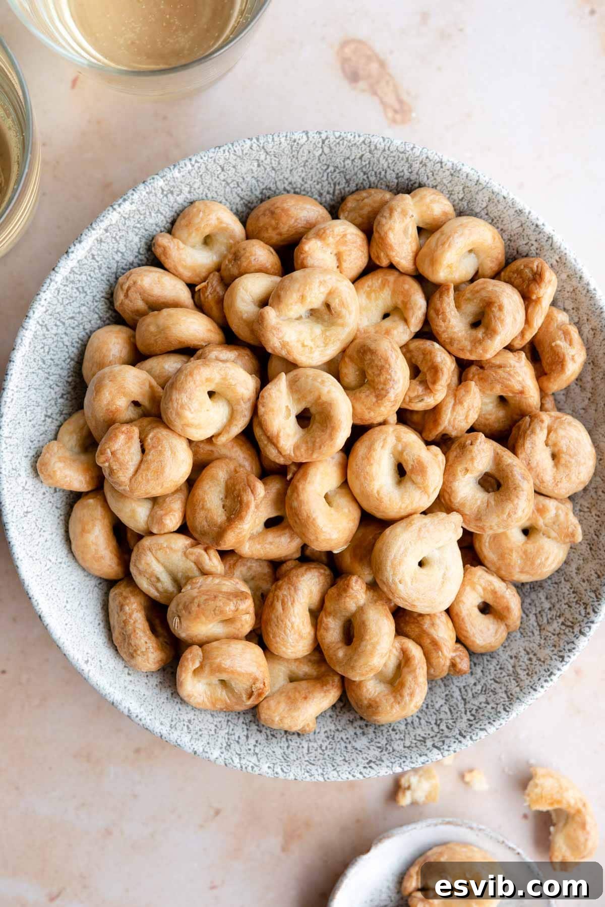 Puglian Taralli Italy's Crunchy Snack Rings 2 An overhead shot of a bowl filled with golden-brown Taralli, with glasses of wine and a bottle in the background, set for an Italian aperitivo, highlighting their perfect snack appeal.