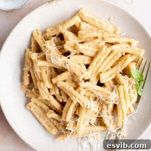 A vibrant bowl of pasta tossed with Pesto alla Trapanese, garnished with fresh basil.