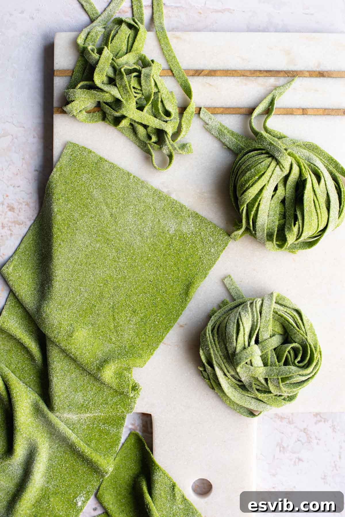 An overhead shot of vibrant green spinach pasta dough cut into various shapes on a light surface, showcasing its fresh texture and appealing color.