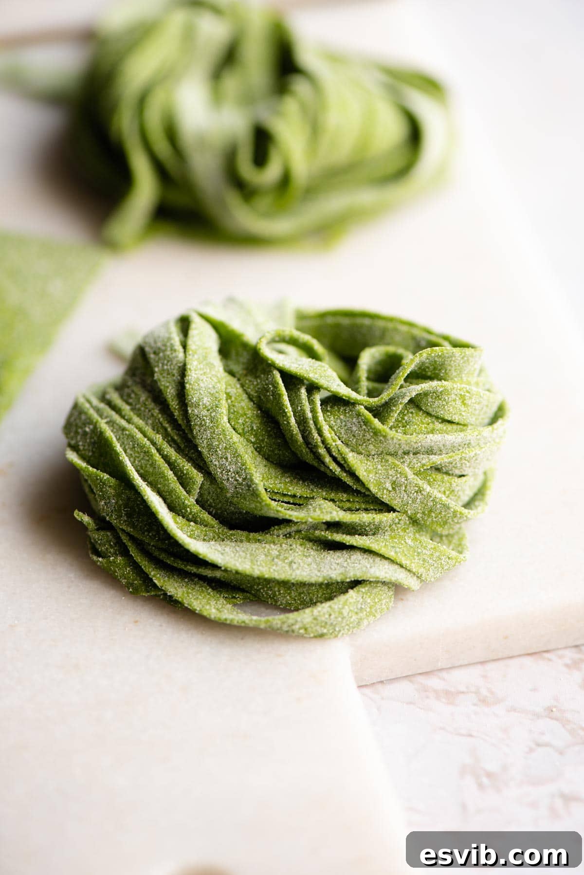 A close up shot of freshly cut, raw spinach tagliatelle, showcasing its vibrant green color and delicate texture.