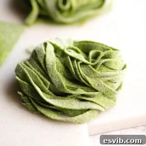 A close up of spinach pasta tagliatelle on a marble cutting board