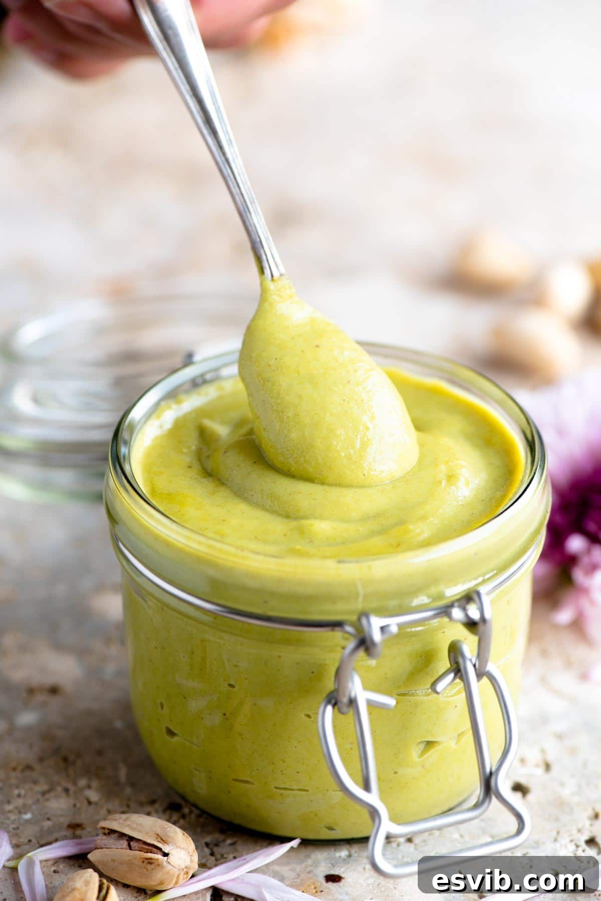 Velvety Italian Pistachio Cream 7 A close up of a spoonful of homemade pistachio cream being lifted from a jar, highlighting its luxurious texture.