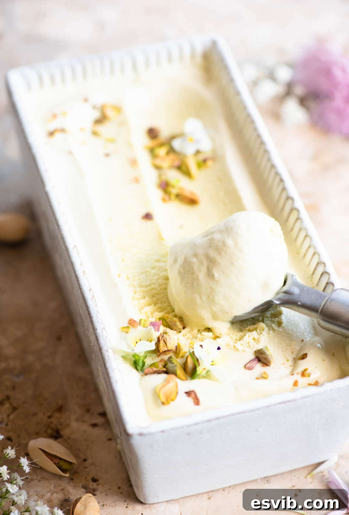 Pistachio ice cream in a loaf dish with a scoop of ice cream at one end, showcasing its elegant presentation.