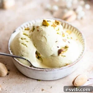 Three scoops of pistachio ice cream in a small bowl with a spoon