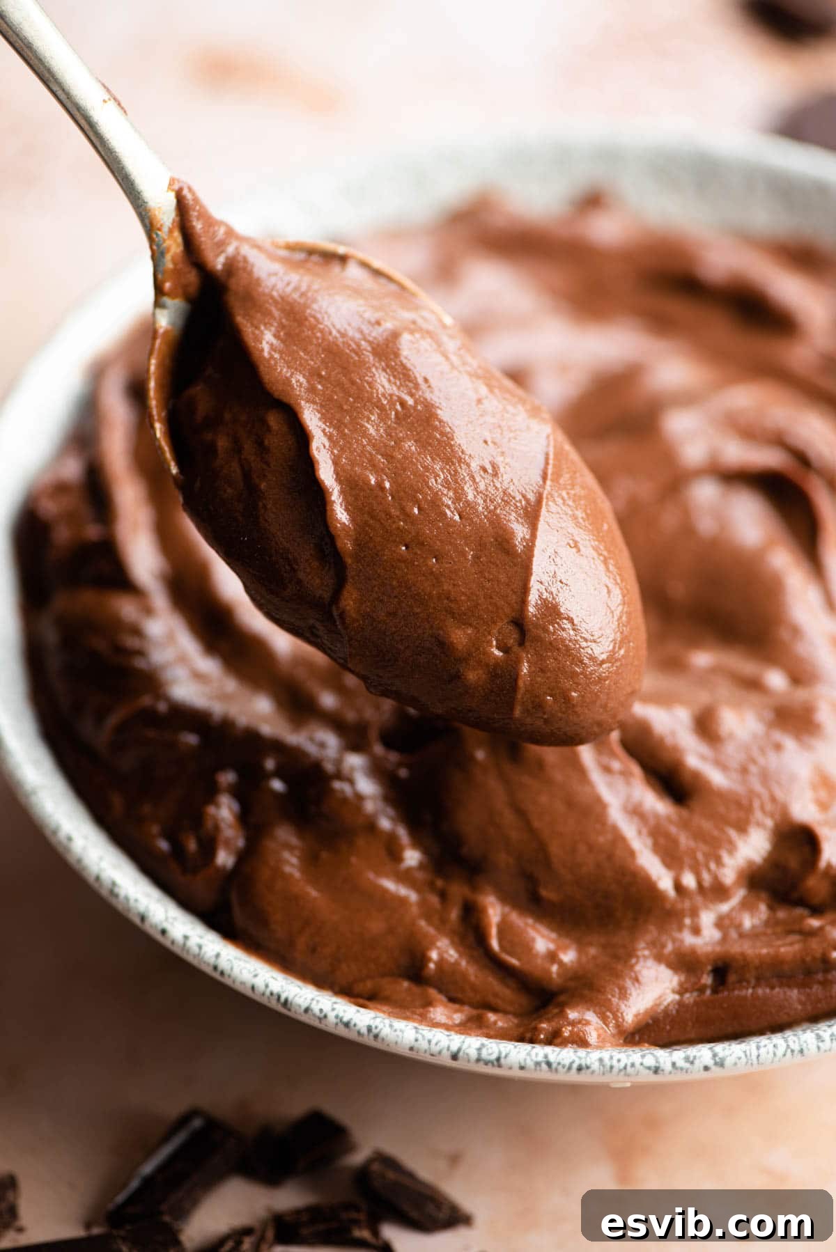 A close-up shot of a spoon delicately scooping a generous amount of rich, glossy Chocolate Pastry Cream, highlighting its smooth and luscious texture.