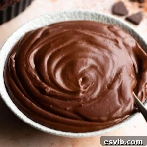 A close up of chocolate pastry cream in a bowl, showing its glossy and smooth texture.