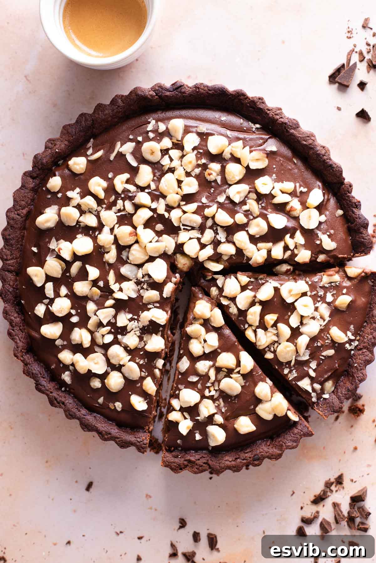 An overhead shot of a chocolate tart topped with hazelnuts