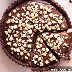 A close up of a chocolate tart topped with chopped hazelnuts