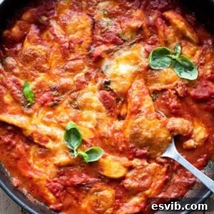 A close up of chicken sorrentina in a skillet, showcasing the melted cheese and rich sauce.