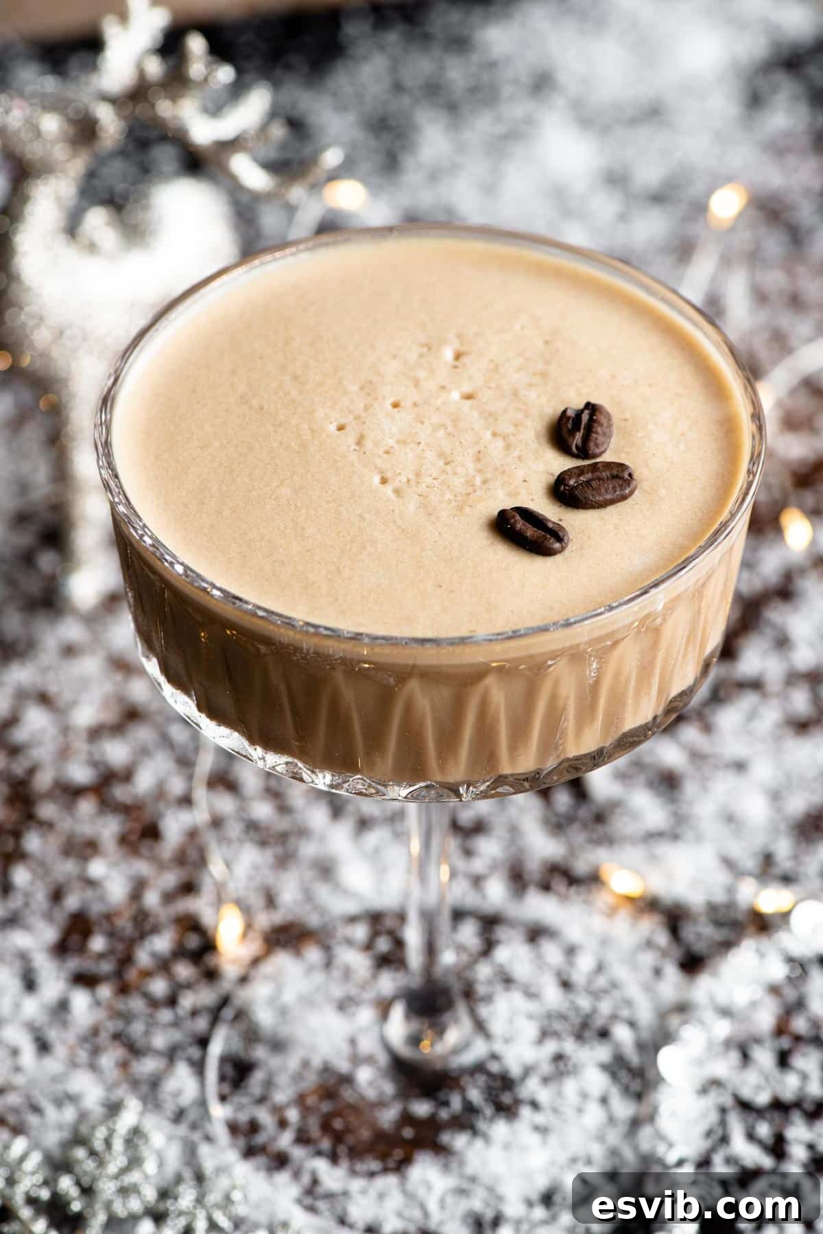 A close up of a martini macchiato in a snowy theme with fairy lights, highlighting its creamy texture and festive appeal.