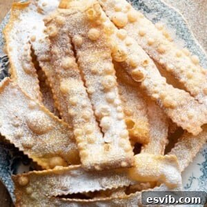 An overhead shot of cenci fried pastries on a plate dusted with sugar
