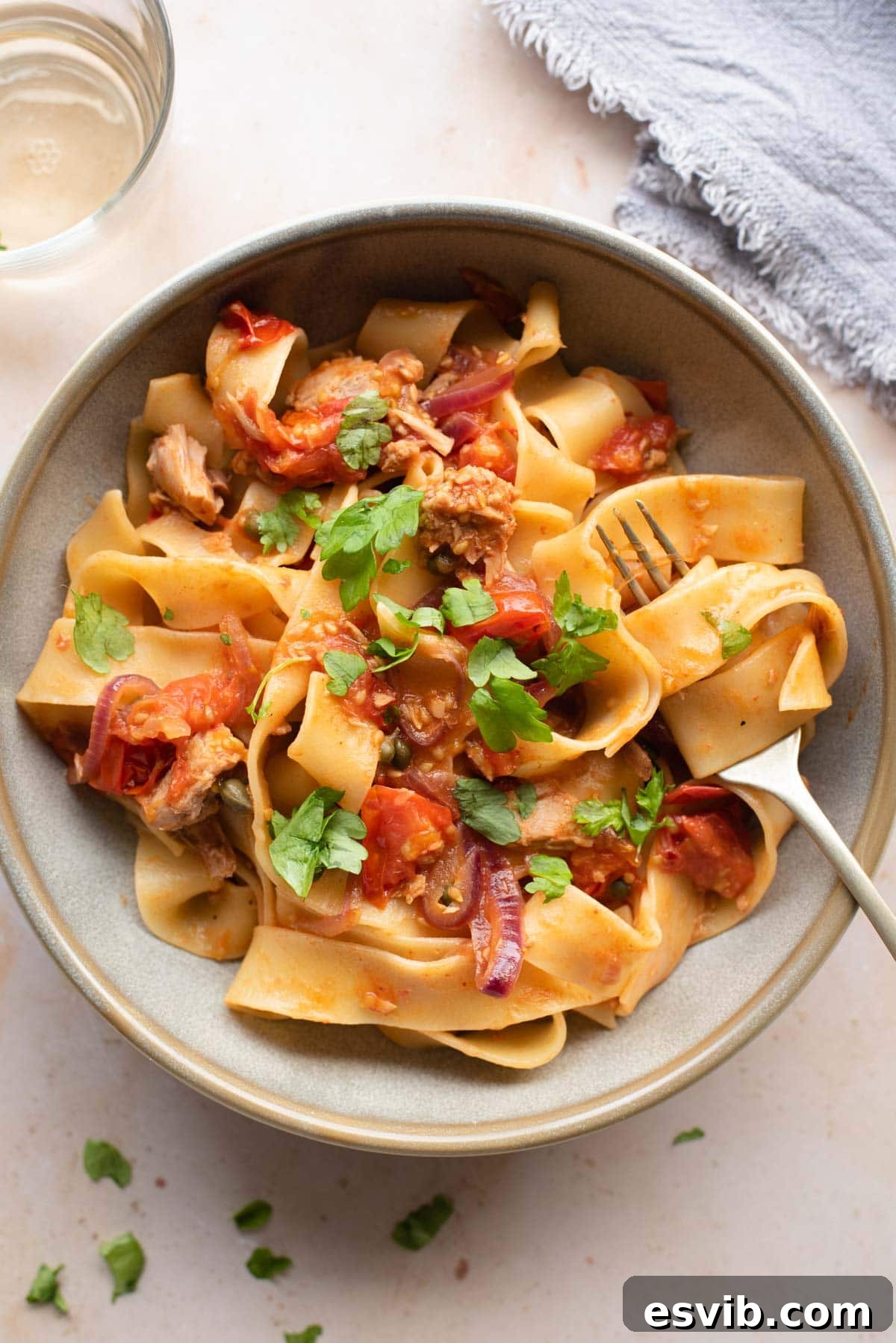 Quick Tuna Tomato and Caper Pasta 2 An overhead shot of tuna pasta in a bowl with tomatoes, capers and parsley