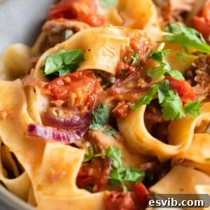 A close up of tuna pasta with tomatoes and parsley
