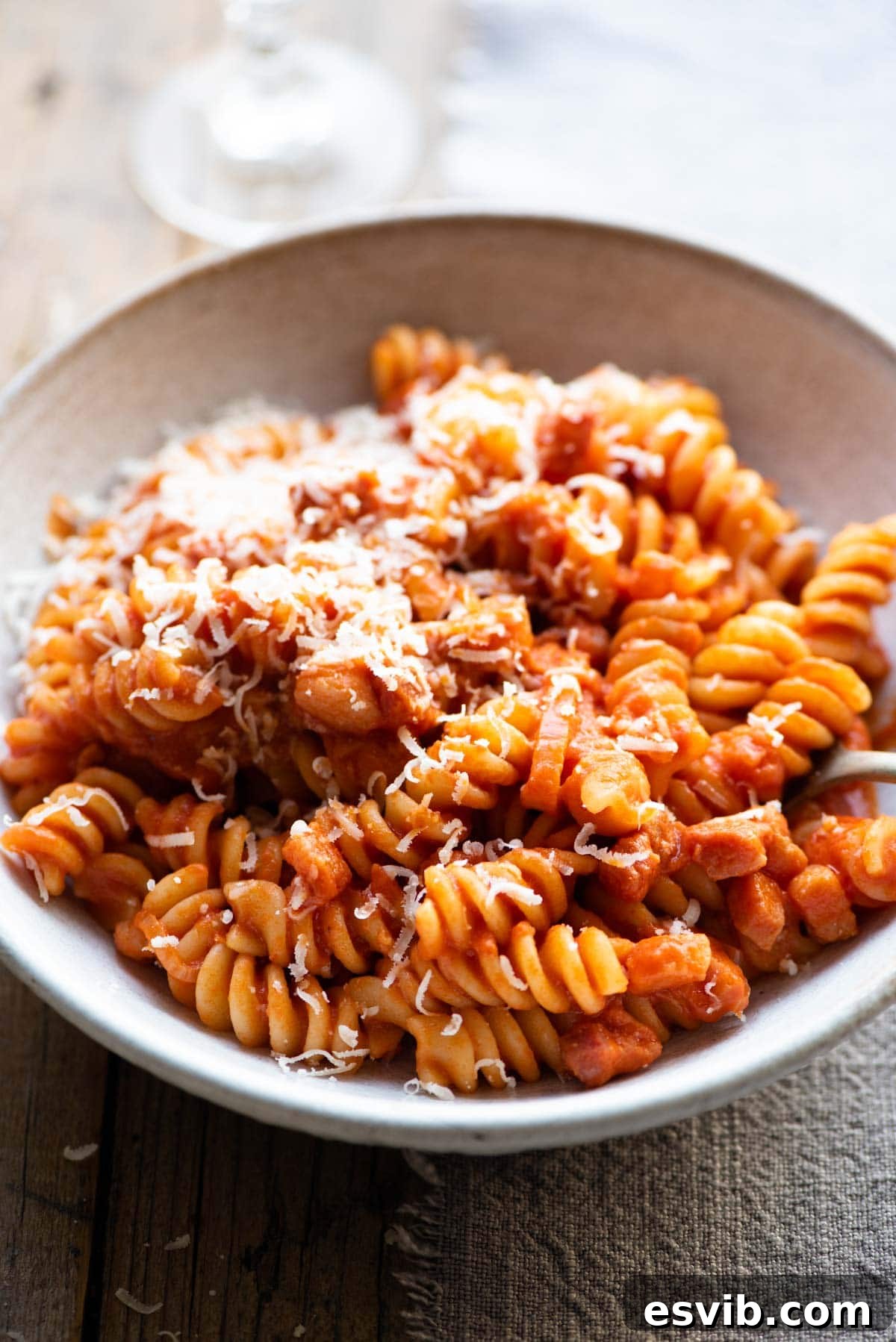 A close up of creamy tomato pasta in a bowl topped with parmesan