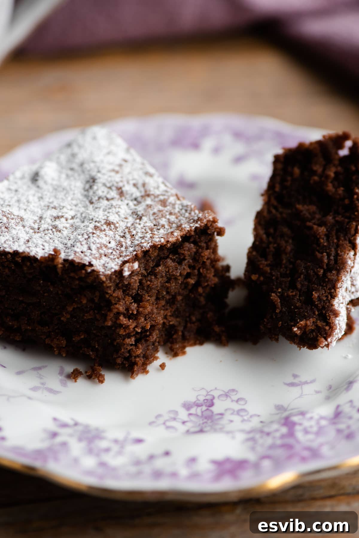 Torta Caprese: Decadent Flourless Italian Chocolate Torte 5 A close-up photograph of a perfectly baked slice of Torta Caprese, elegantly cut in half, revealing its dense, moist, and rich chocolate interior, indicative of its exquisite texture.