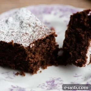 Torta Caprese: Decadent Flourless Italian Chocolate Torte 6 A perfectly baked slice of Torta Caprese cake on a white plate, cut in half to showcase its rich, dense, and moist texture, ready to be enjoyed.