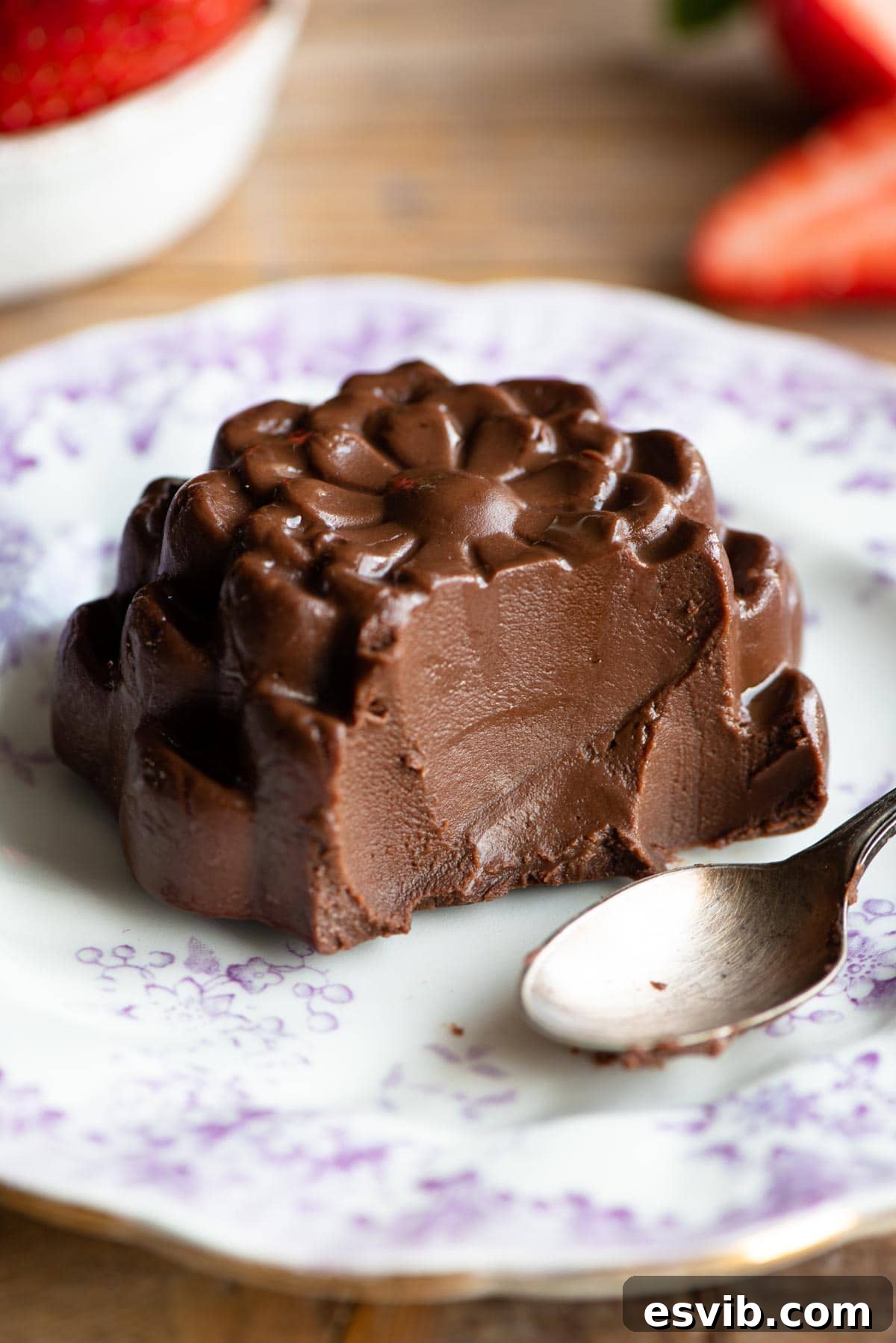 A tantalizing close-up shot of a Chocolate Budino with a spoonful removed, revealing its incredibly smooth and rich interior, resting on a small white plate.