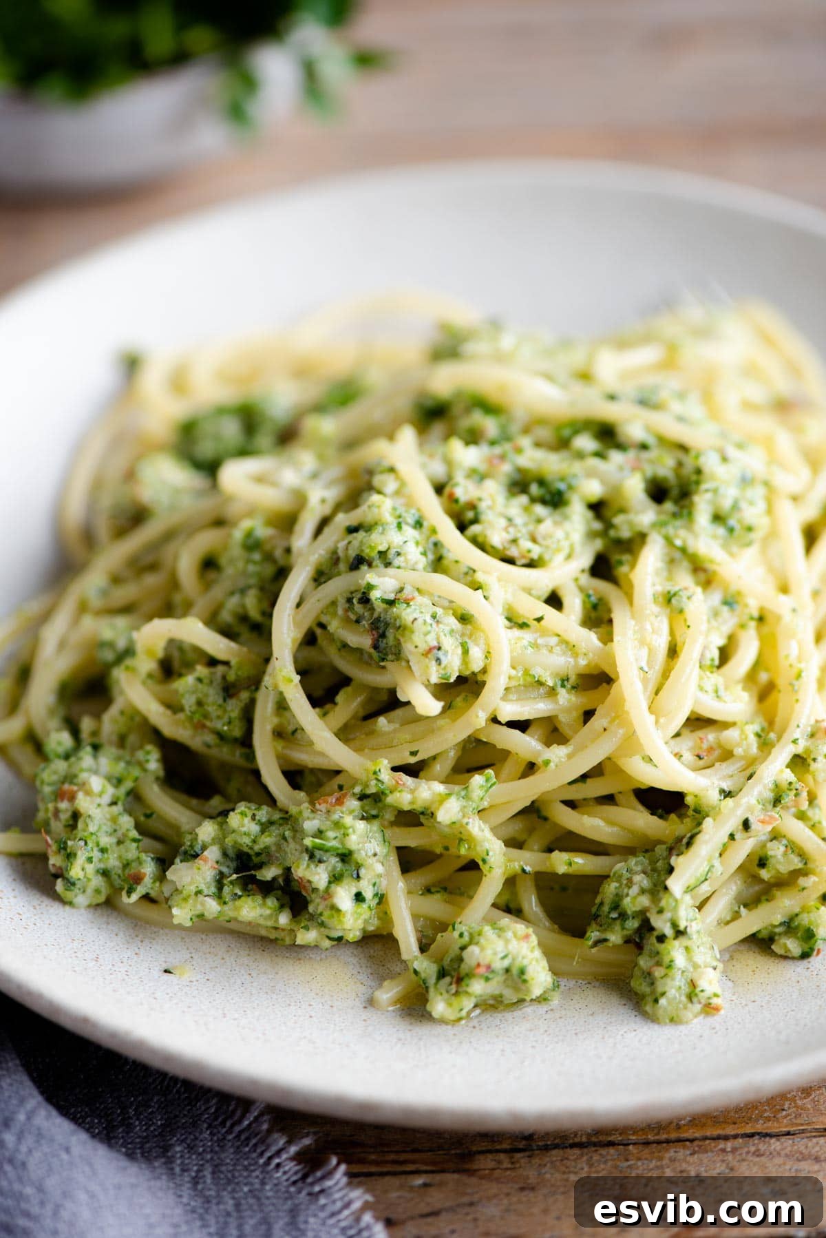 A close-up shot of spaghetti generously coated with vibrant zucchini pesto on a ceramic plate