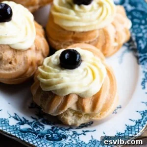 A close up of a Zeppole (Italian pastry) topped with custard and a cherry on top sitting on a blue plate