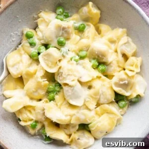 A close up of Tortellini alla Panna in a bowl with peas