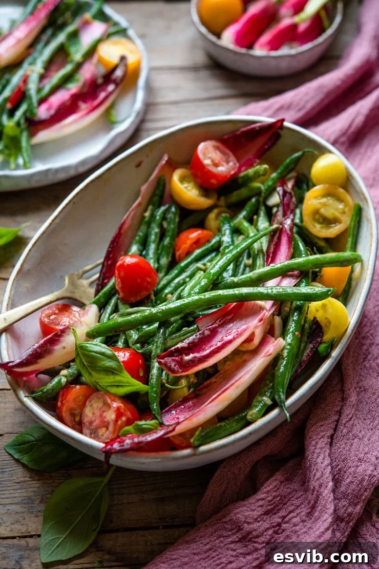 A beautiful side shot of a large serving bowl filled with the fresh green bean salad, highlighting its vibrant colors and textures.