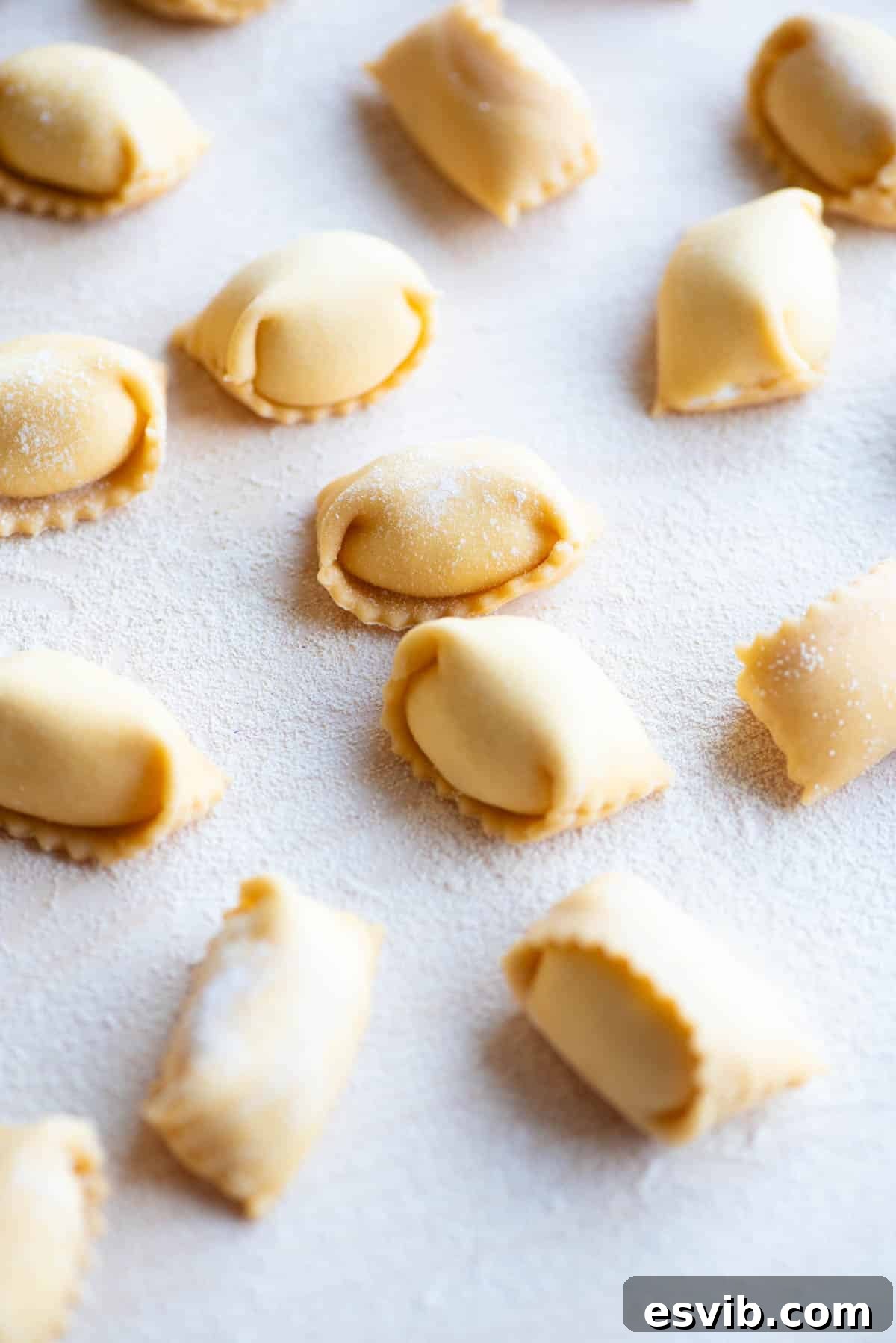 A close-up side view of beautifully shaped homemade Agnolotti pasta on a rustic wooden board.