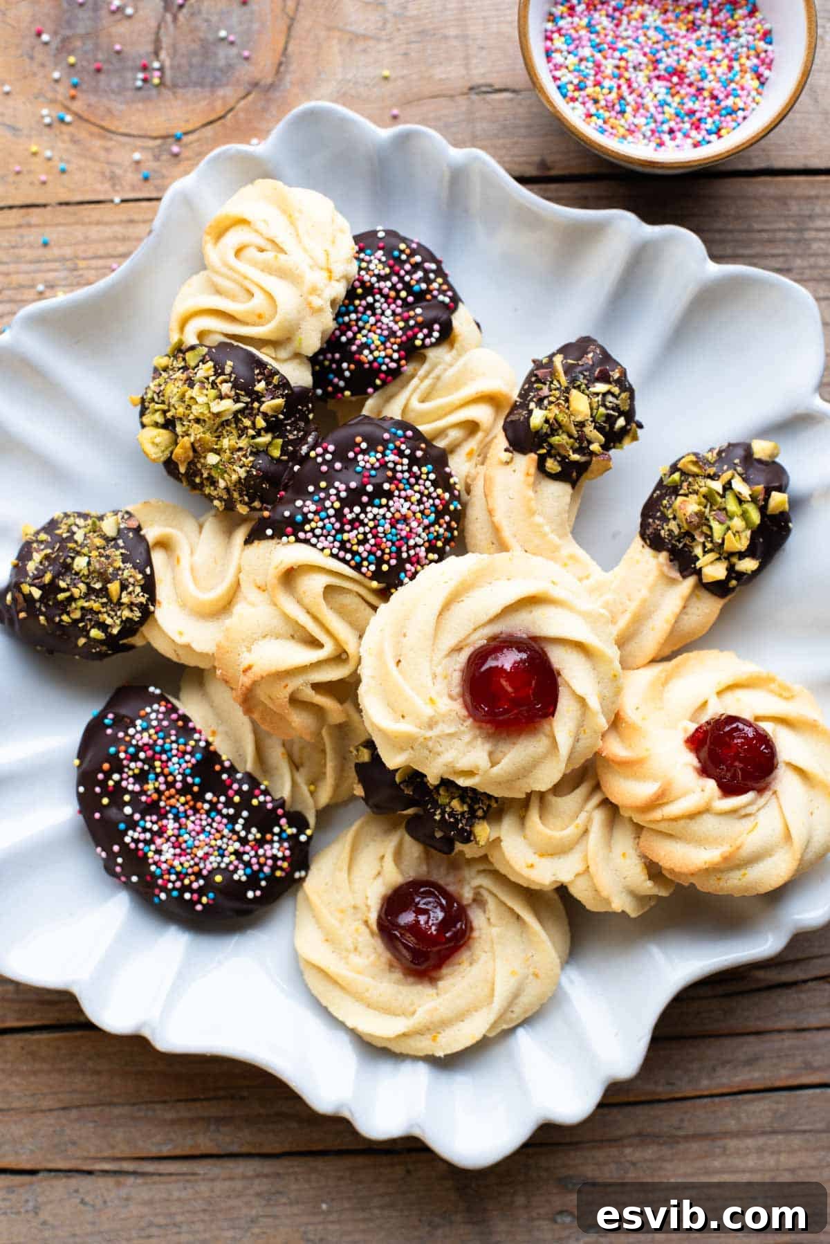 Italian Whipped Butter Cookies 2 An overhead shot of beautifully arranged Italian butter cookies on a star-shaped plate, garnished with a delightful mix of chopped nuts and colorful sprinkles. The rustic wooden background provides a warm, inviting setting for these homemade treats.