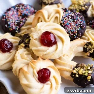 A close up of Italian butter cookies on a plate. In the centre is a round cookie with a candied cherry on top.