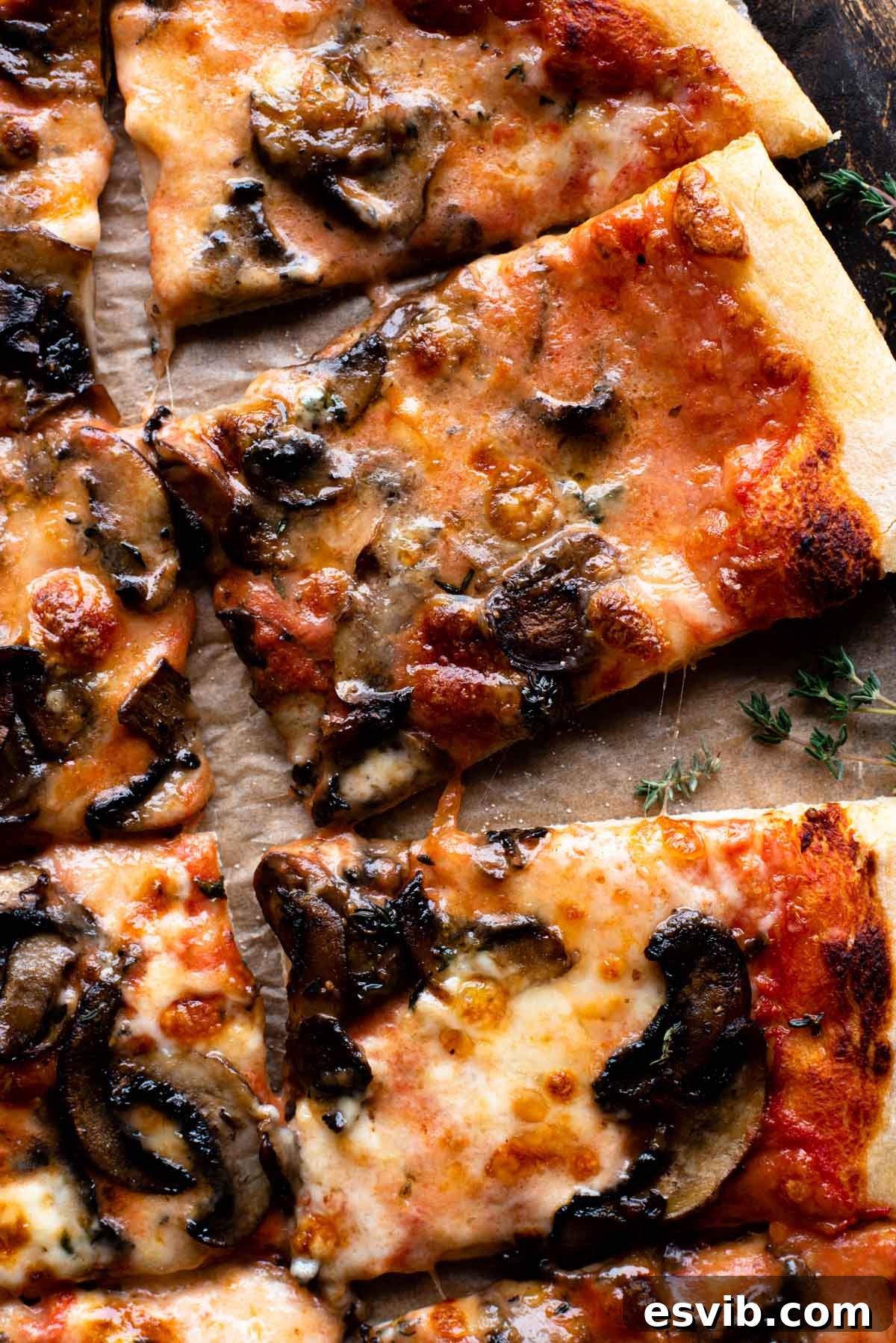 Creamy Taleggio Wild Mushroom Pizza 7 A close-up shot of a gourmet mushroom pizza, highlighting the melted Taleggio cheese, fresh herbs, and golden crust, resting on a rustic wooden surface.