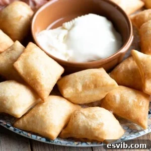 A close-up square image of Gnocco Fritto (Italian fried dough) on a plate with cheese, showcasing its golden-brown crispness.