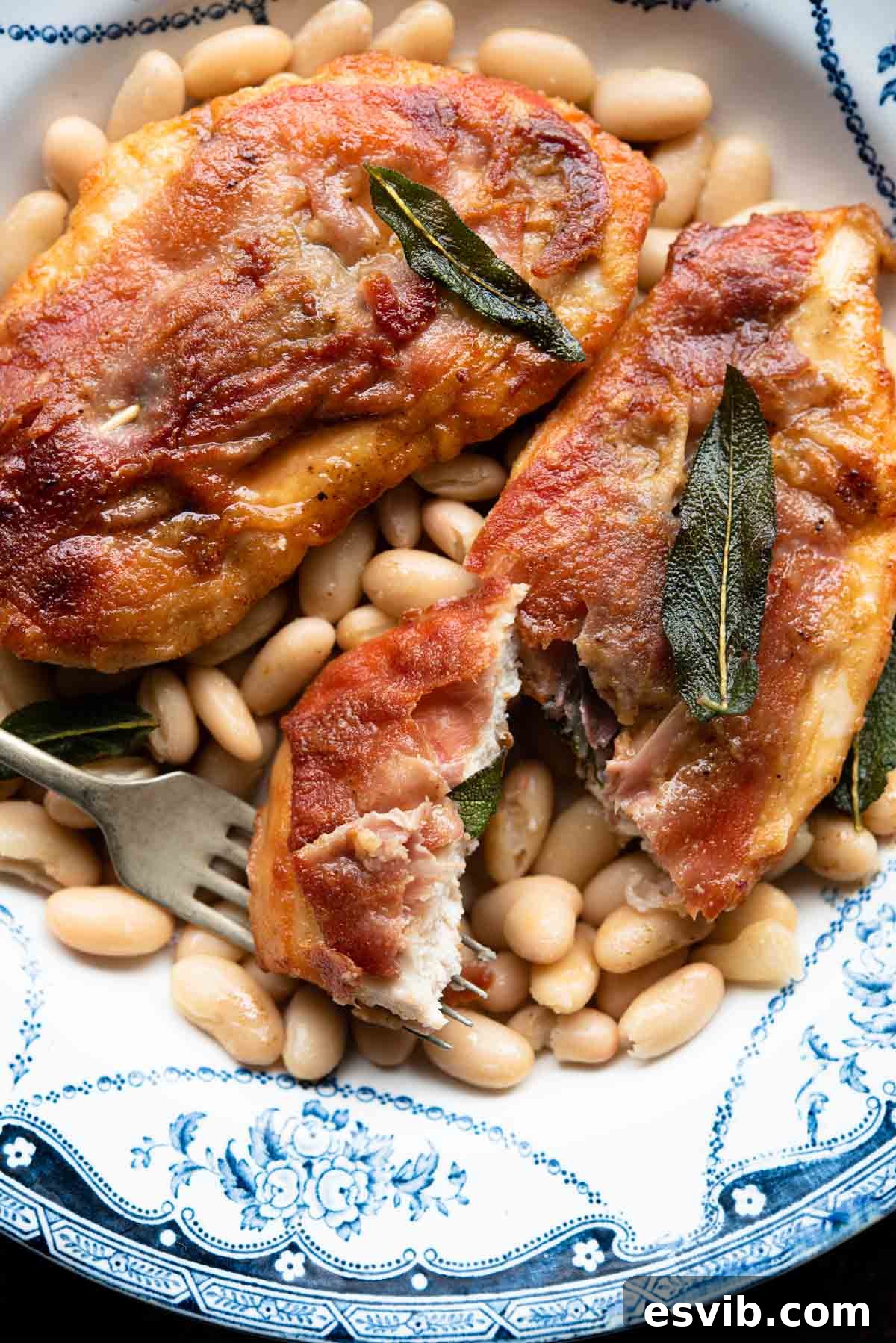 A close up of chicken saltimbocca on a plate with beans and sage.