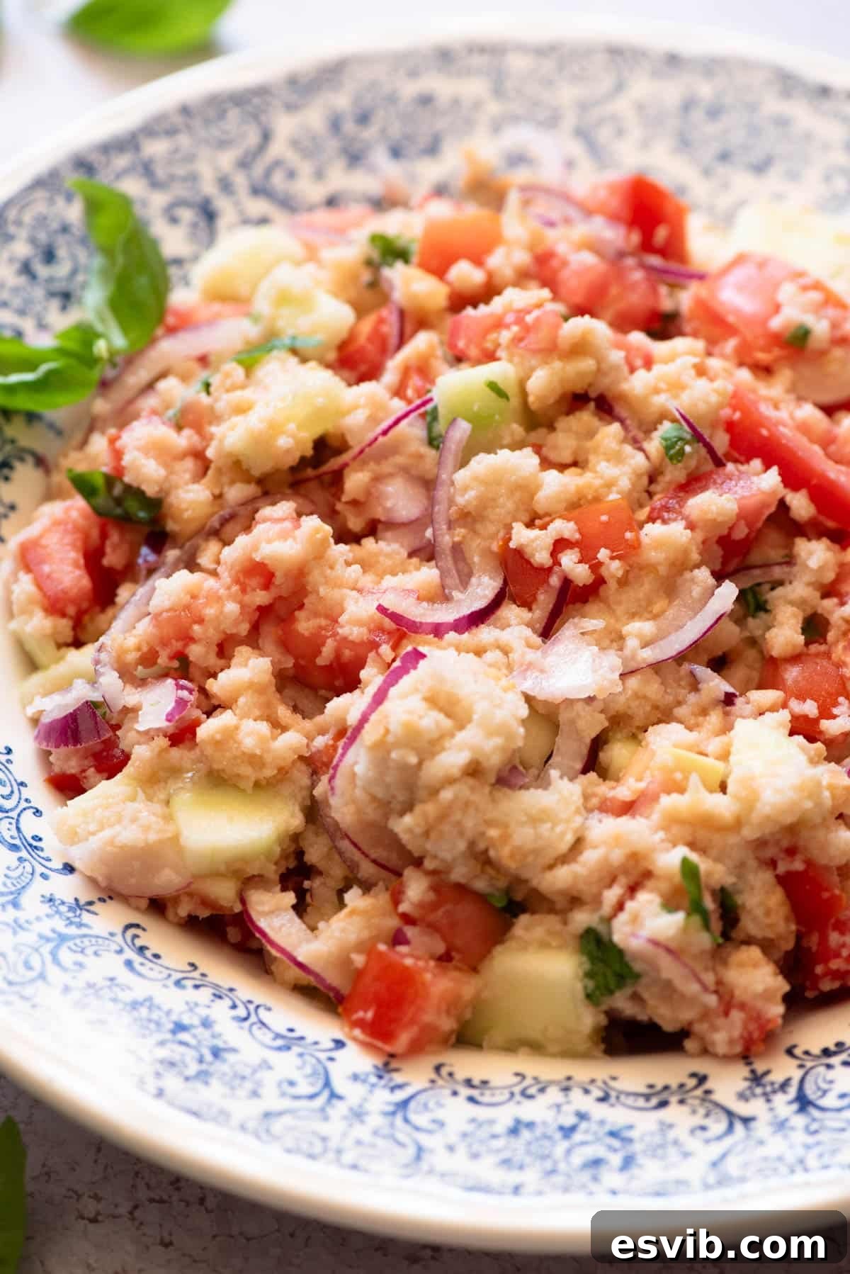 Rustic Tuscan Panzanella 5 A close-up of authentic Panzanella salad, highlighting the vibrant colors and textures of the tomatoes, cucumber, onion, and bread, in a blue bowl.