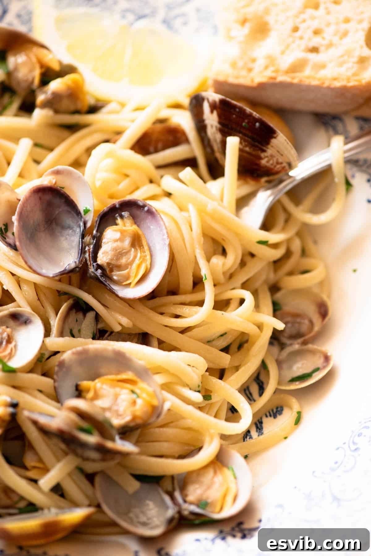 A mouth-watering close-up of linguine pasta with fresh clams, vibrant parsley, and a hint of lemon, beautifully arranged in a bowl.