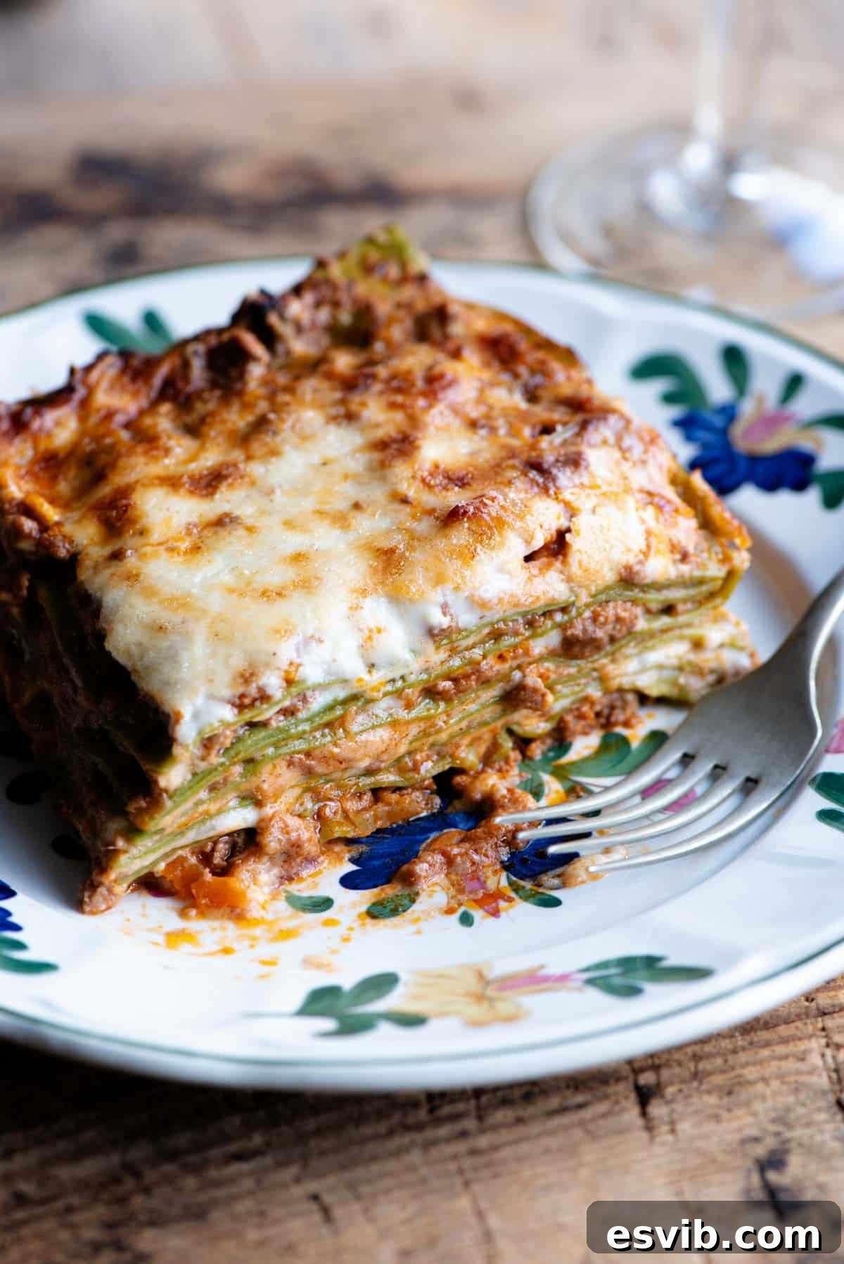 A close-up shot of a delectable slice of Lasagna Bolognese presented on an elegant plate with a subtle floral pattern, inviting a culinary experience.