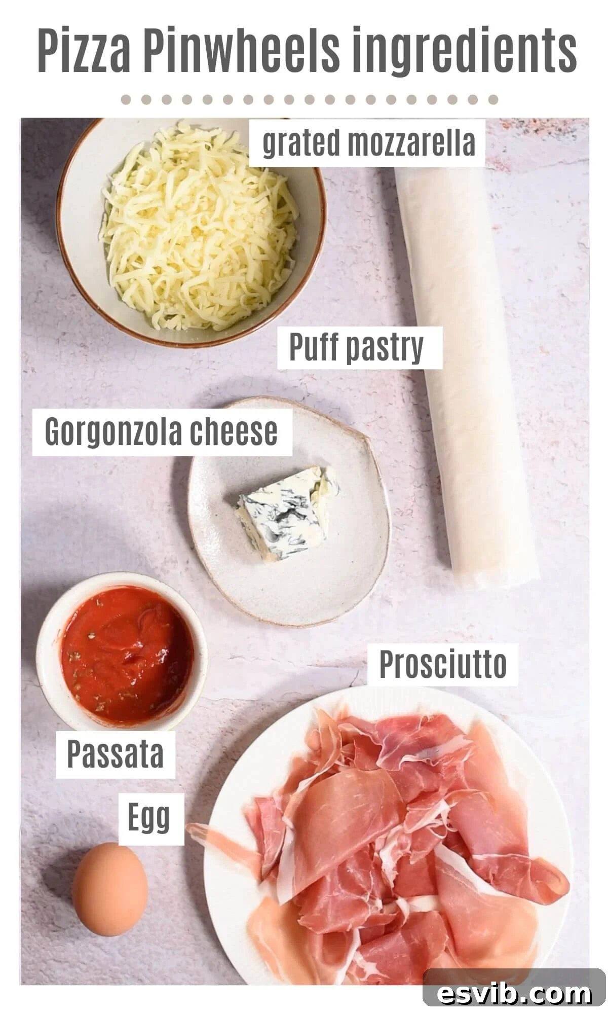 A flat lay photograph displaying all the fresh and high-quality ingredients needed to prepare Prosciutto Gorgonzola Pizza Pinwheels: a sheet of puff pastry, passata, dried oregano, slices of prosciutto, crumbled Gorgonzola, grated mozzarella, and a beaten egg.