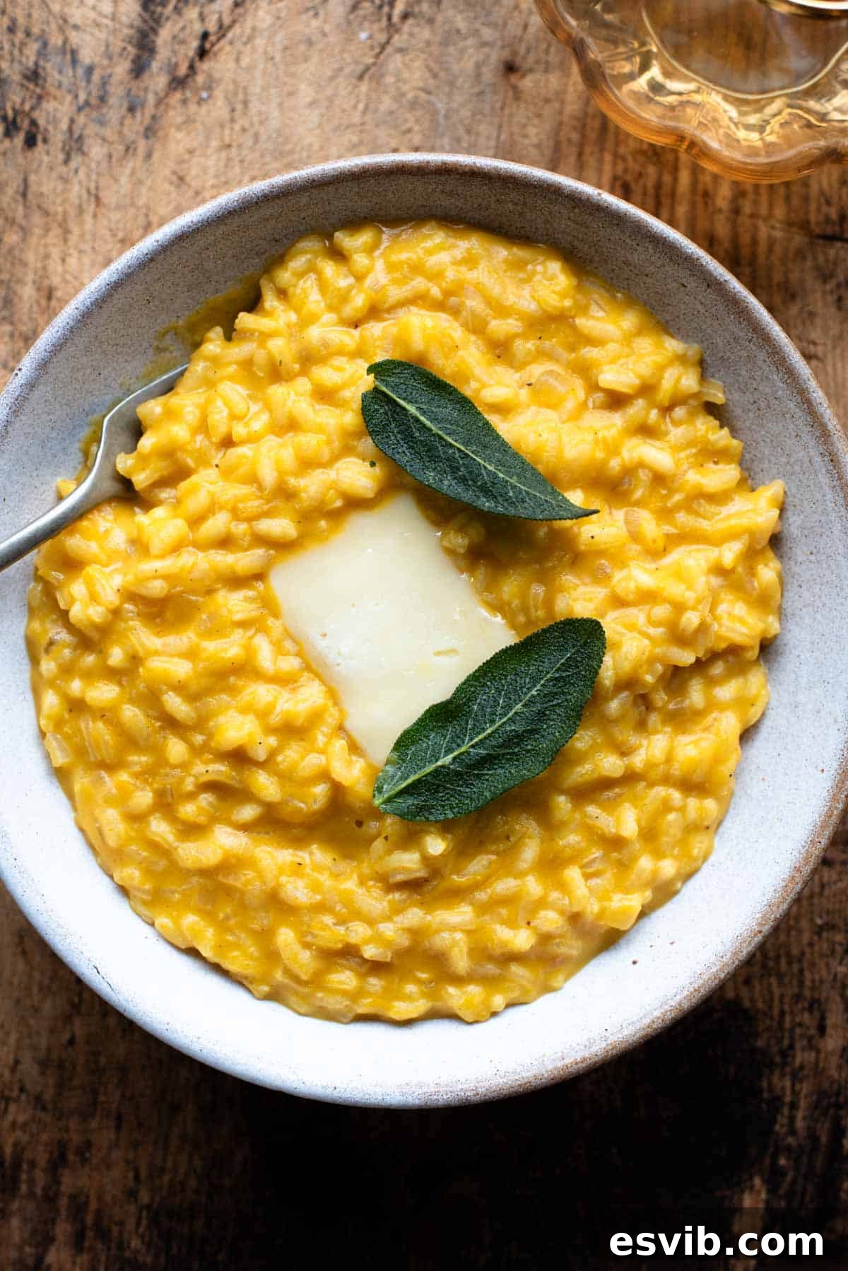 An overhead shot of a Pumpkin Risotto with a slice of Taleggio cheese and crispy sage on top.