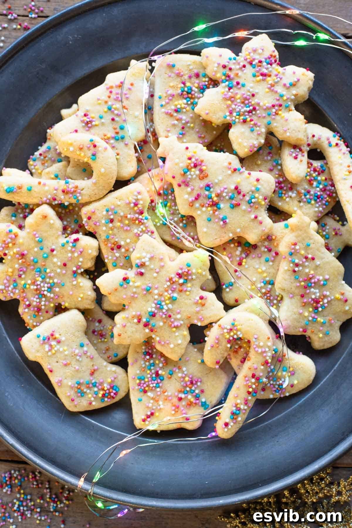 An overhead shot of Befanini Tuscan Christmas cookies cut into Christmas shapes on a plate topped with sprinkles, evoking a festive holiday mood.