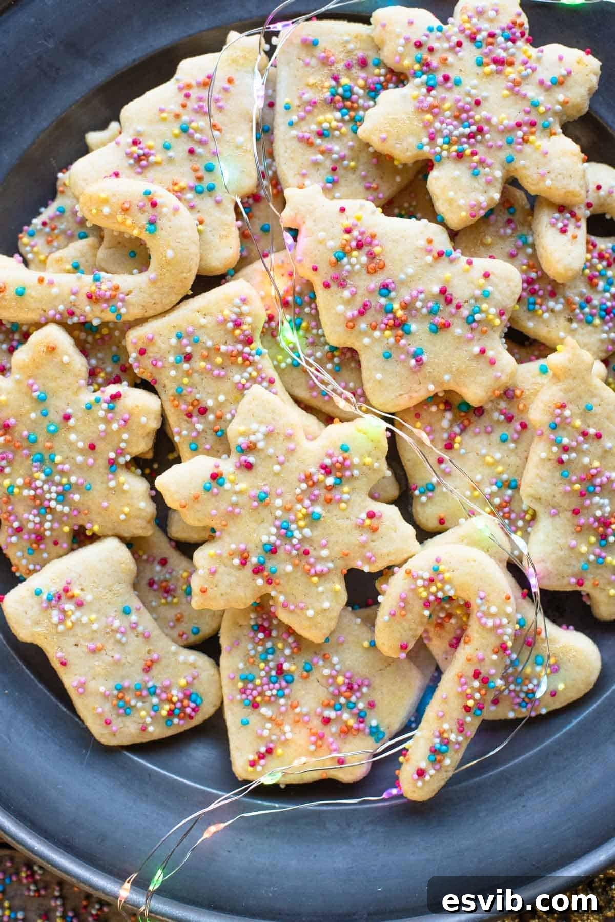 A close up of freshly baked Befanini Christmas cookies on a plate, adorned with colorful sprinkles.