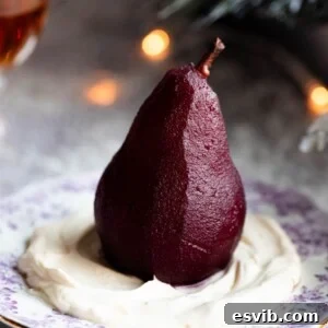 Amaretto Red Wine Poached Pears A close-up of a perfectly poached red wine pear served over a bed of light Amaretto whipped cream on a small dessert plate.