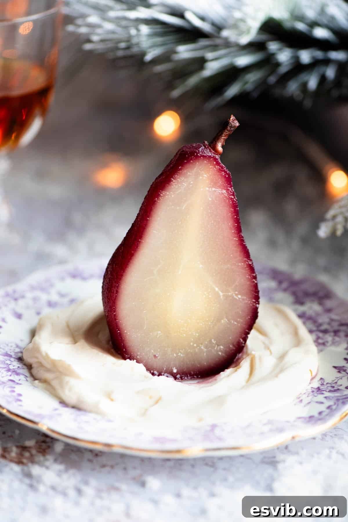 Exquisite Sliced Amaretto Red Wine Poached Pears A beautifully presented red wine poached pear, artfully sliced in half and fanned out on a white plate, accompanied by a generous dollop of Amaretto whipped cream and subtle festive garnishes in the background.